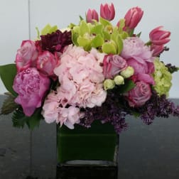 Pink and green mixed flower arrangement in a square glass vase