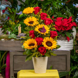 Bouquet of red roses and yellow sunflowers in a white vase