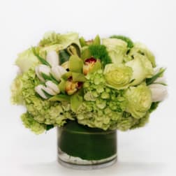 Green and white floral arrangement in a glass vase