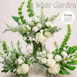 White floral arrangement in a glass vase with tall green spikes