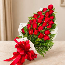 Bouquet of red roses wrapped in white paper with a red ribbon