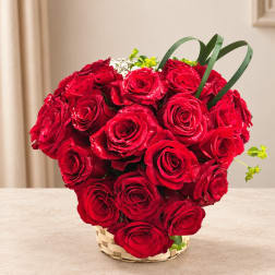 Basket of red roses with small white flowers and green accents