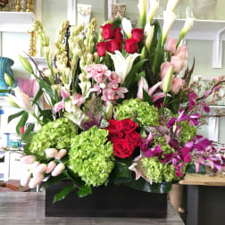 Large mixed floral arrangement with red roses, white calla lilies, and pink orchids