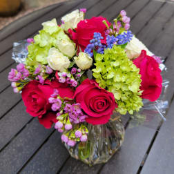Bouquet of pink roses, white roses, and green hydrangeas in a glass vase