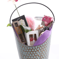 Gift basket with chocolates, candles, and a pink orchid stem
