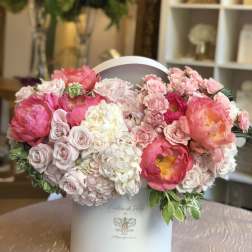 Pink and white floral arrangement in a white hatbox