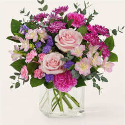 Pink roses and mixed blooms in a clear glass vase