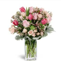 Pink tulips and roses arranged in a clear glass vase