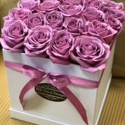 Pink roses arranged in a white square box with a ribbon bow
