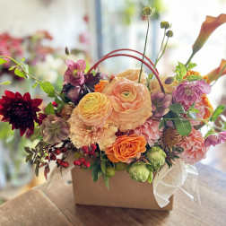Mixed floral arrangement in a square box with peach, pink, orange, and burgundy blooms