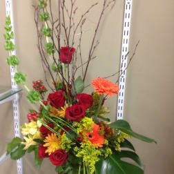 Tall mixed bouquet with red roses and orange gerbera daisies in a vase