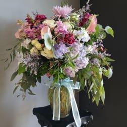 Large mixed bouquet in a glass vase with a pale ribbon