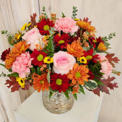 Mixed bouquet of pink, red, orange, and yellow flowers in a silver vase