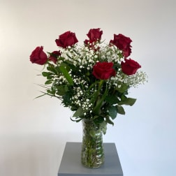 Red roses in a clear glass vase with baby's breath