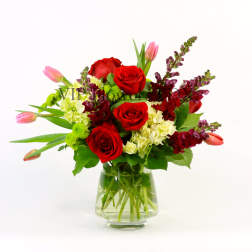 Red roses and pink tulips in a clear glass vase