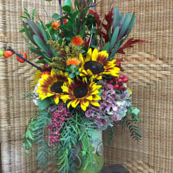 Sunflower arrangement in a green vase with berries and autumn foliage