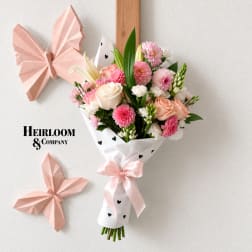 Pink and white bouquet wrapped in paper with a satin ribbon