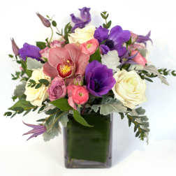 Bouquet of purple, pink, and white flowers in a square glass vase