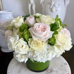 White and pale pink roses arranged in a green vase
