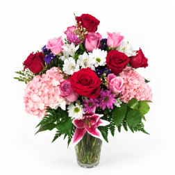 Bouquet of red and pink roses with white daisies in a glass vase