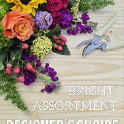 Bright mixed bouquet with roses, sunflower, and purple blooms beside pruning shears