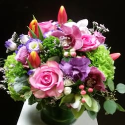 Mixed bouquet of pink, purple, and white flowers in a glass vase