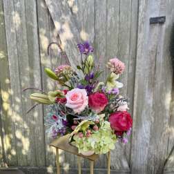 Mixed bouquet with pink roses, lilies, and purple blooms in a vase