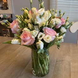 Pink and white flowers arranged in a clear glass vase