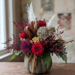 Arrangement of red roses and purple flowers in a gray pumpkin vase