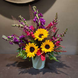 Bright mixed bouquet with yellow sunflowers in a pale vase