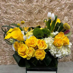 Yellow roses and white flowers arranged in a black container