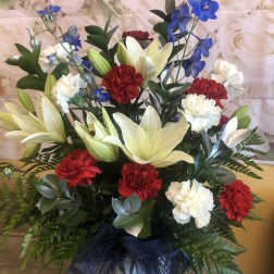 Arrangement of white lilies, red and white carnations, and blue delphinium in a vase