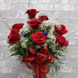 Red roses arranged in a clear glass vase with a red ribbon bow