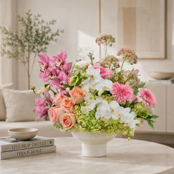 Mixed pink, white, and peach flowers arranged in a white vase