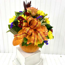 Fall floral arrangement in a pumpkin container with an orange ribbon bow