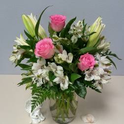 Pink roses and white lilies in a clear glass vase