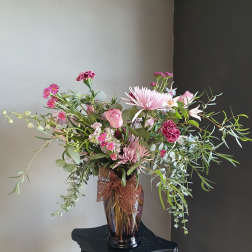 Pink mixed bouquet in a glass vase with a brown ribbon
