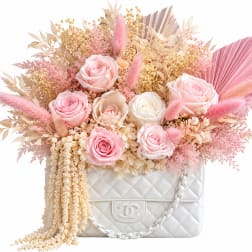 Pink and cream roses arranged in a white quilted handbag