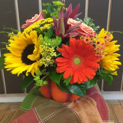 Bright mixed bouquet with sunflowers and gerbera daisies in a pumpkin vase
