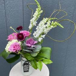 Pink and white floral arrangement in a white vase with looping branches