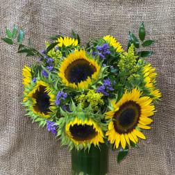 Sunflower bouquet in a glass vase with purple filler flowers