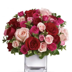 Bouquet of red, pink, and blush roses in a clear glass vase
