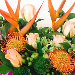 Tropical bouquet with orange heliconia, peach roses, and orange pincushion blooms