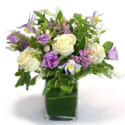 Purple and white mixed bouquet in a square glass vase