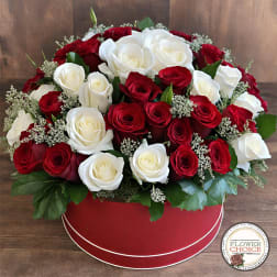 Red and white roses arranged in a round red box