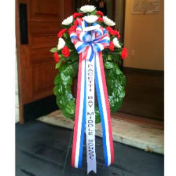 Red and white floral standing wreath with a ribbon bow and long streamers
