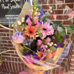 Colorful mixed bouquet with gerbera daisies, roses, and snapdragons in clear wrap