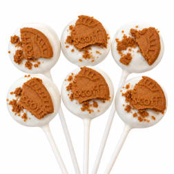 Six white cake pops topped with broken cookie pieces on sticks