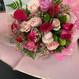 Bouquet of pink, lavender, and white roses wrapped in pink paper