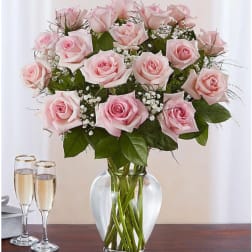Pink roses arranged in a clear glass vase with baby's breath